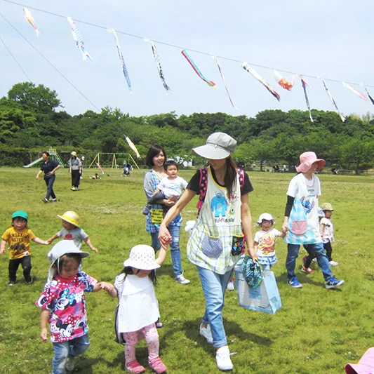 公園でこいのぼりの下を歩く子どもたちと保育士